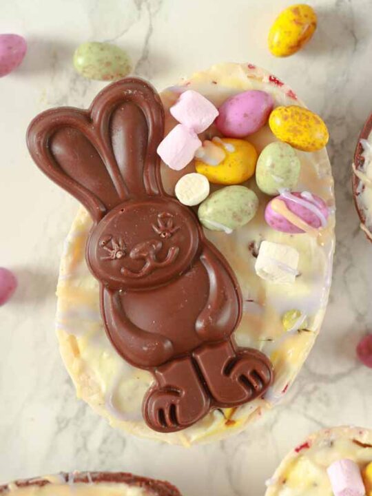 a chocolate bunny on top of a white cheesecake filled Easter egg