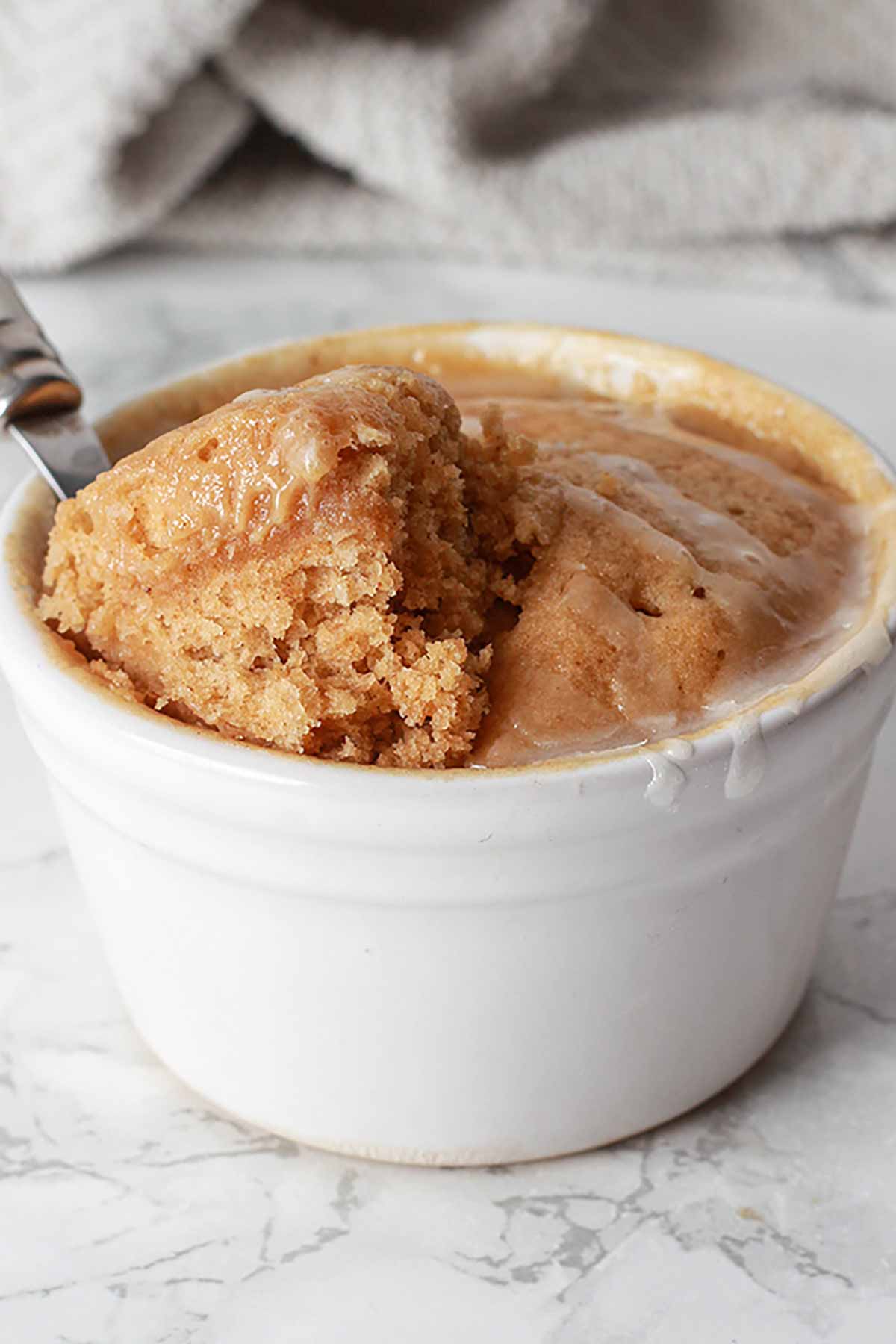 A Spoonful Of Fluffy Mug Cake Resting On The Cake