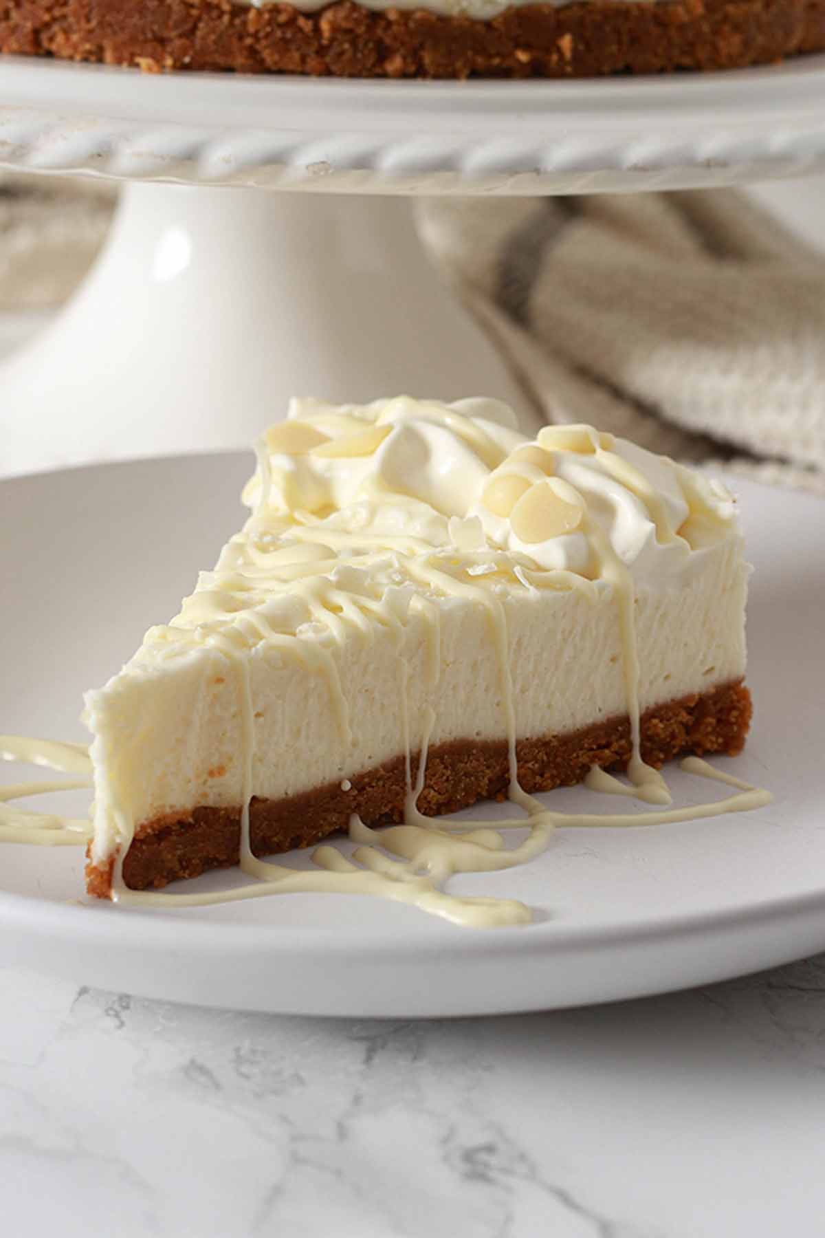 Cheesecake Slice On Plate With White Chocolate Drizzled On Top
