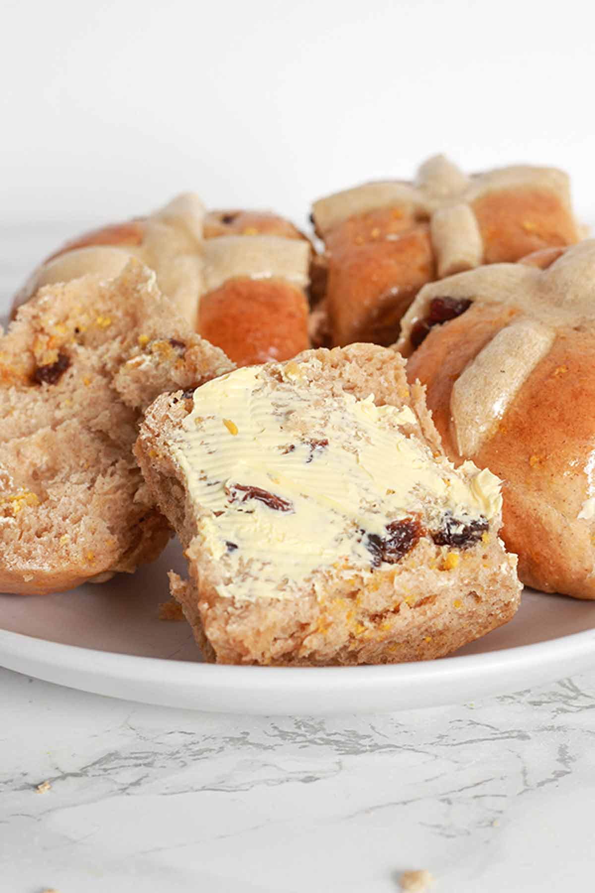 Hot Cross Buns On A Plate, One Is Cut Open With Margarine Spread On Top