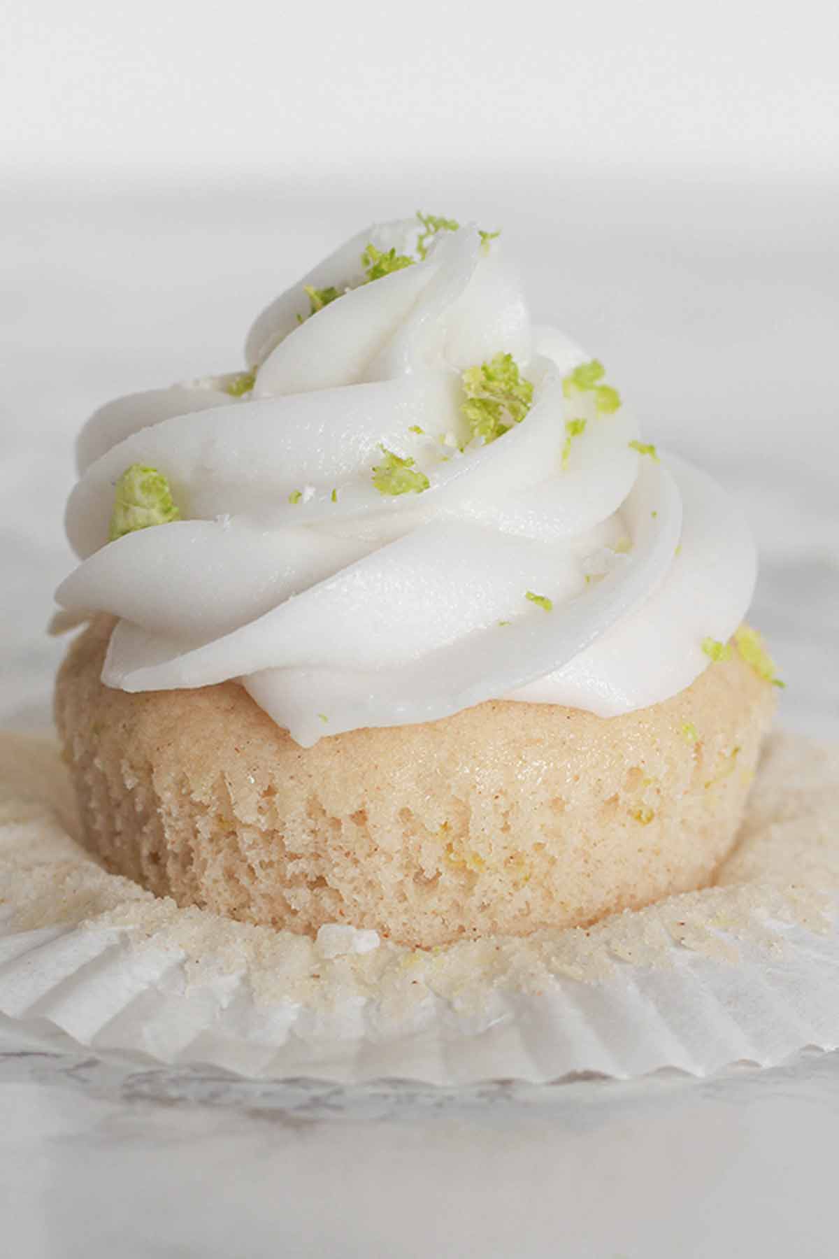 A Single Cupcake Topped With Coconut Frosting And Lime Zest