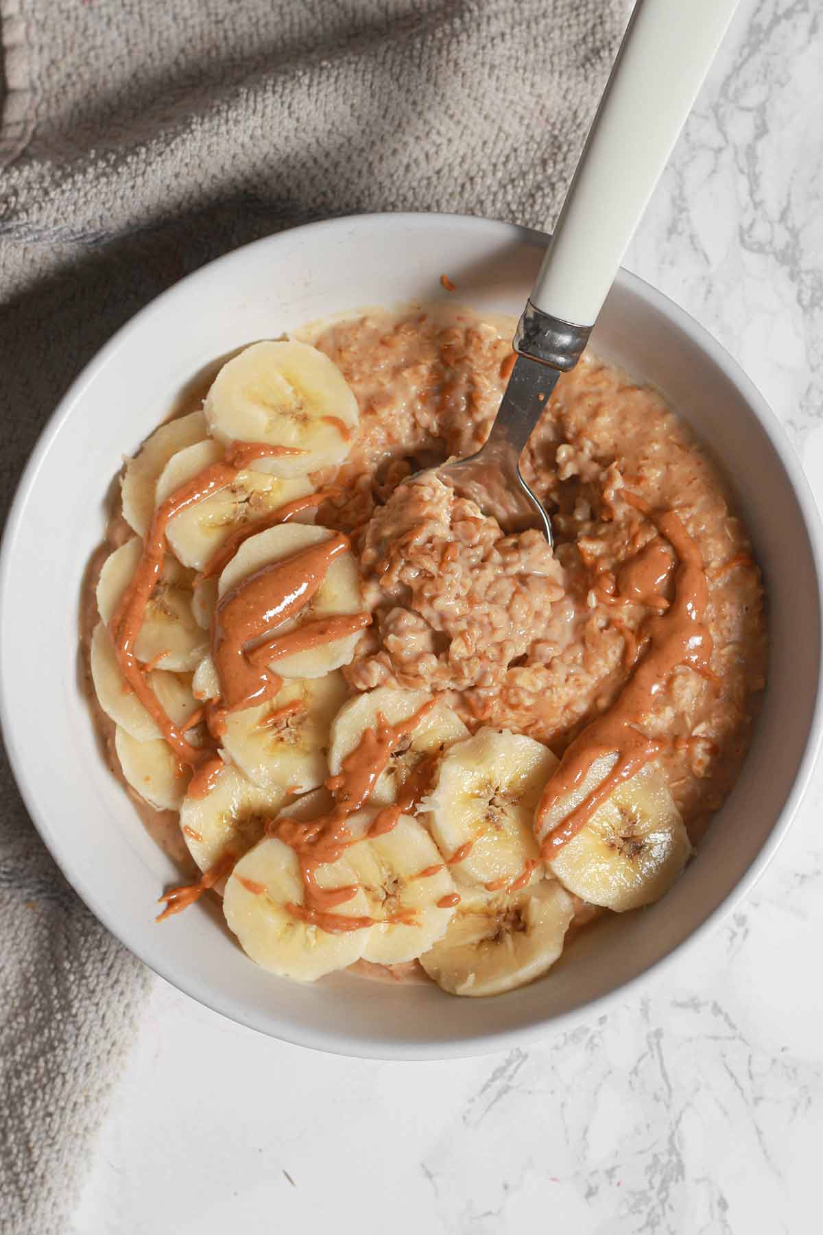 Peanut Butter Porridge In A Bowl With Banana Slices On Top