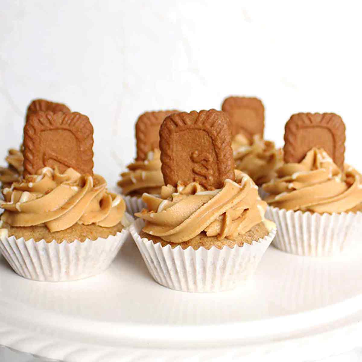 6 Vegan Biscoff Cupcakes On A White Cake Stand
