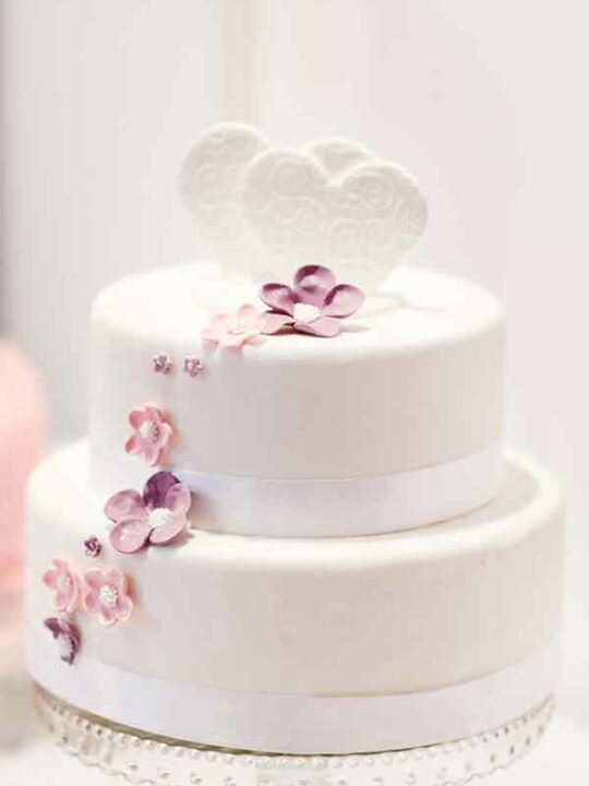 A Two Tier Cake Covered With Fondant Icing