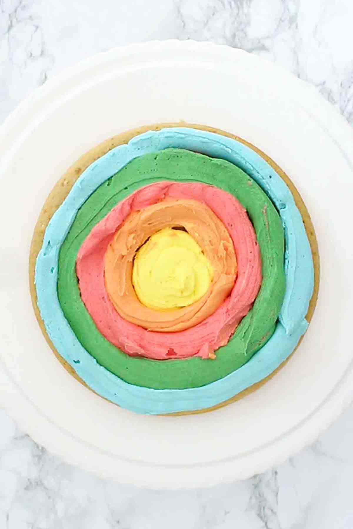 Cake On A Cakestand With Rainbow Frosting On It
