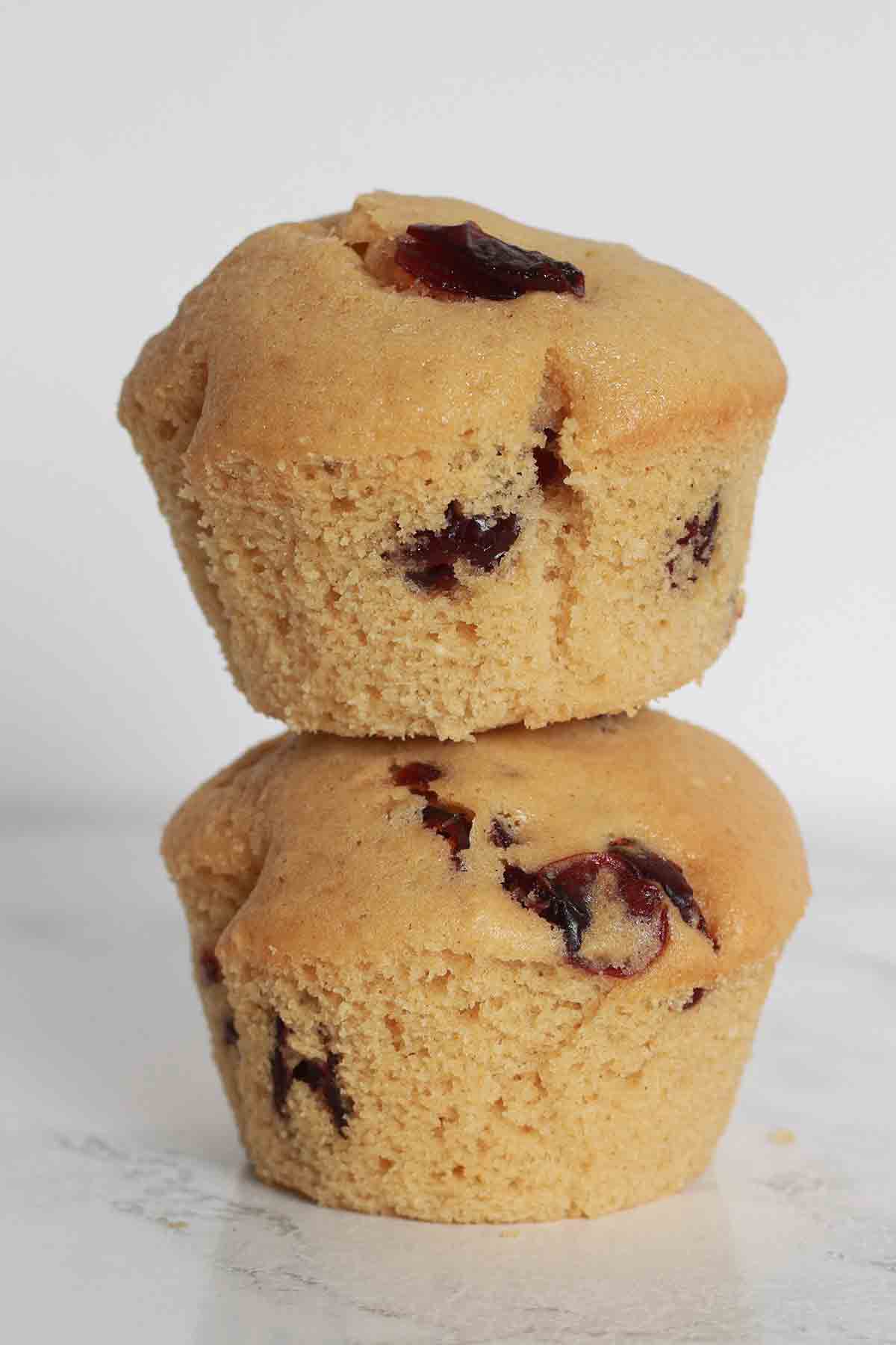 Two Eggless Cranberry Muffins Stacked On Top Of One Another