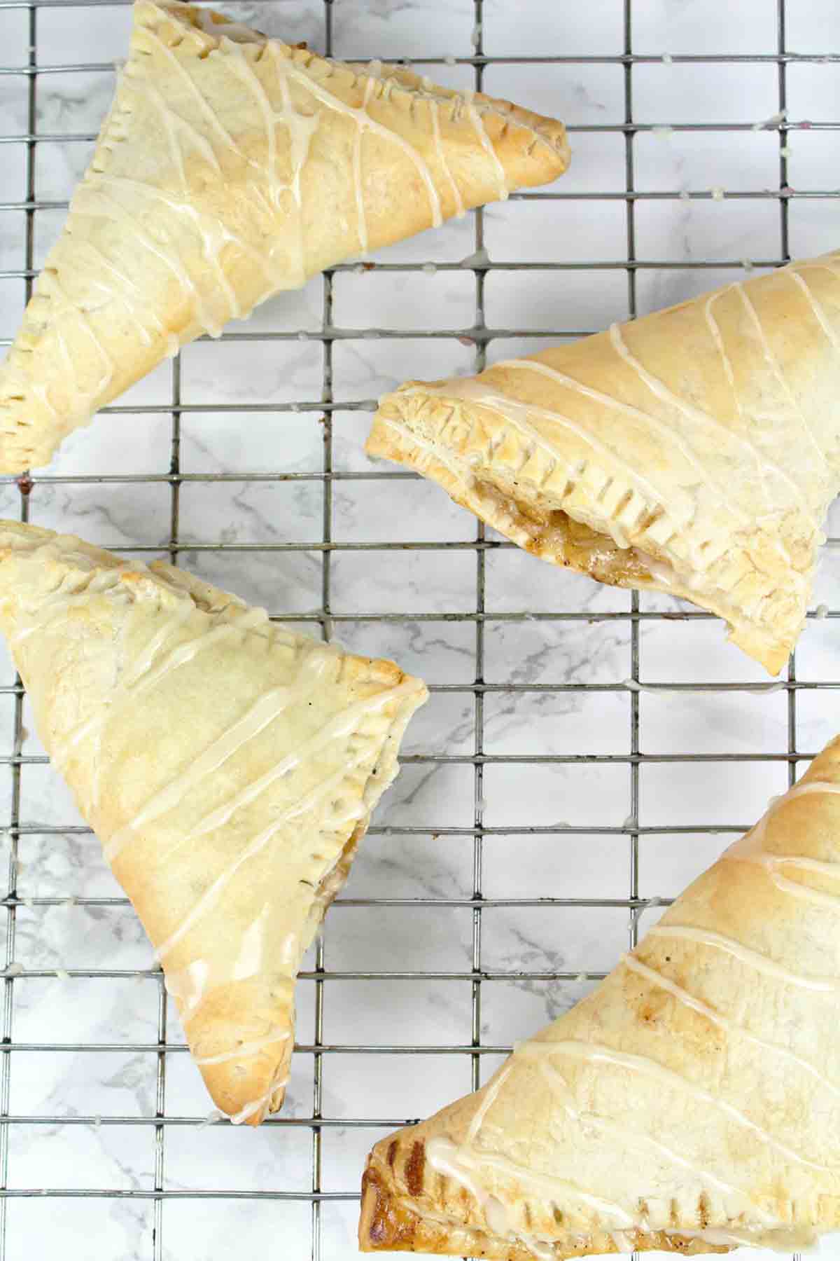 4 Dairy Free Apple Turnovers On A Wire Rack With Icing