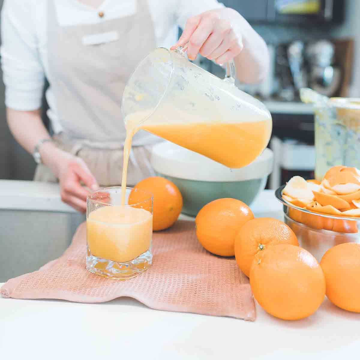 Woman Pouring Orange Juice Into A Glass