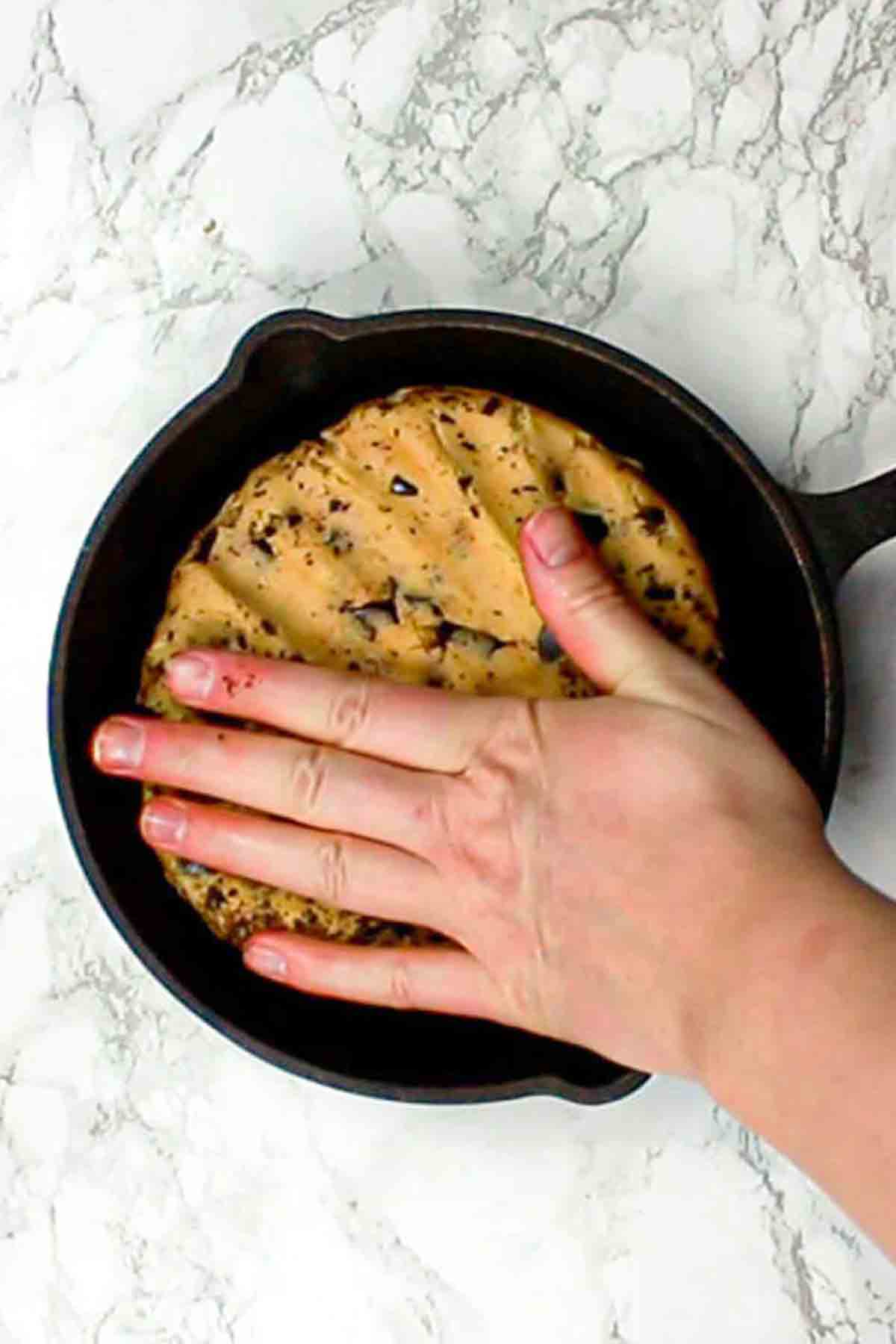Pressing Cookie Dough Into A Cast Iron Skillet