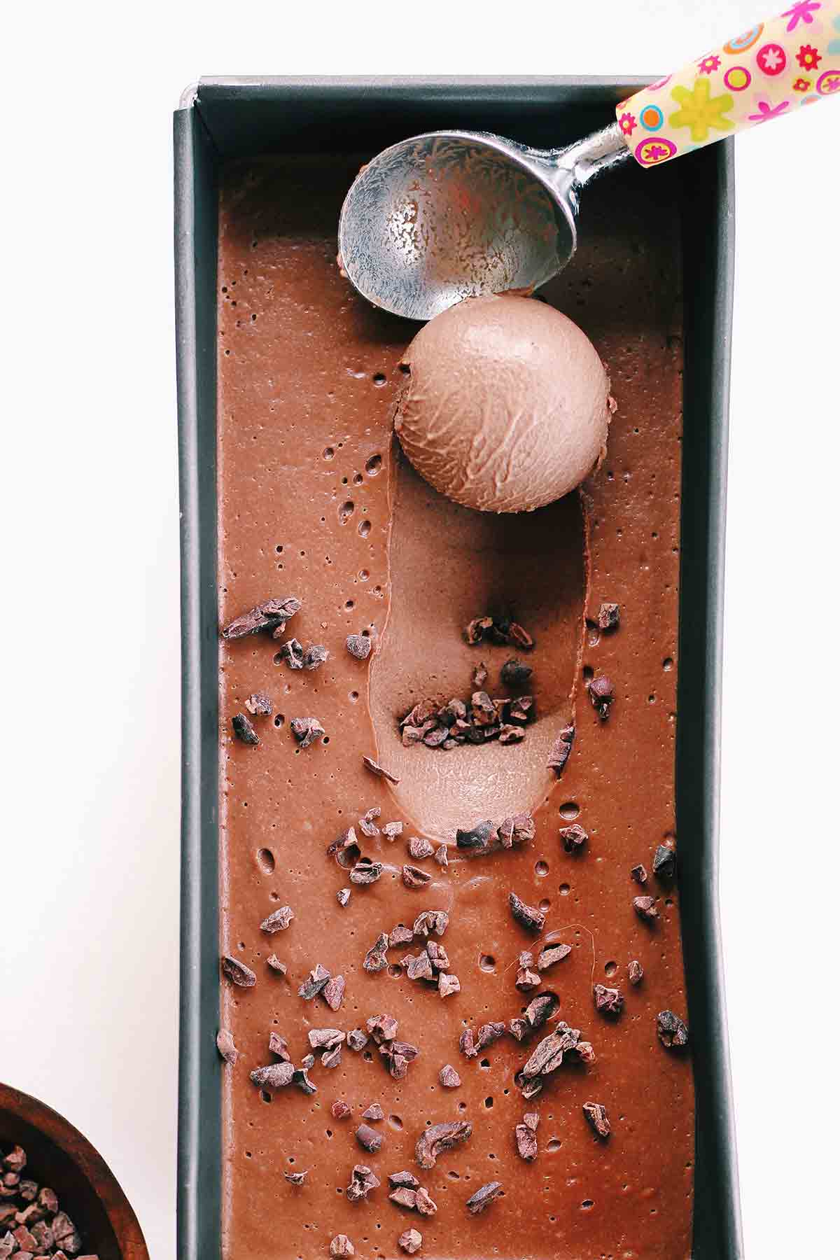 Chocolate Gelato In A Tub With A Scoop Being Taken Out