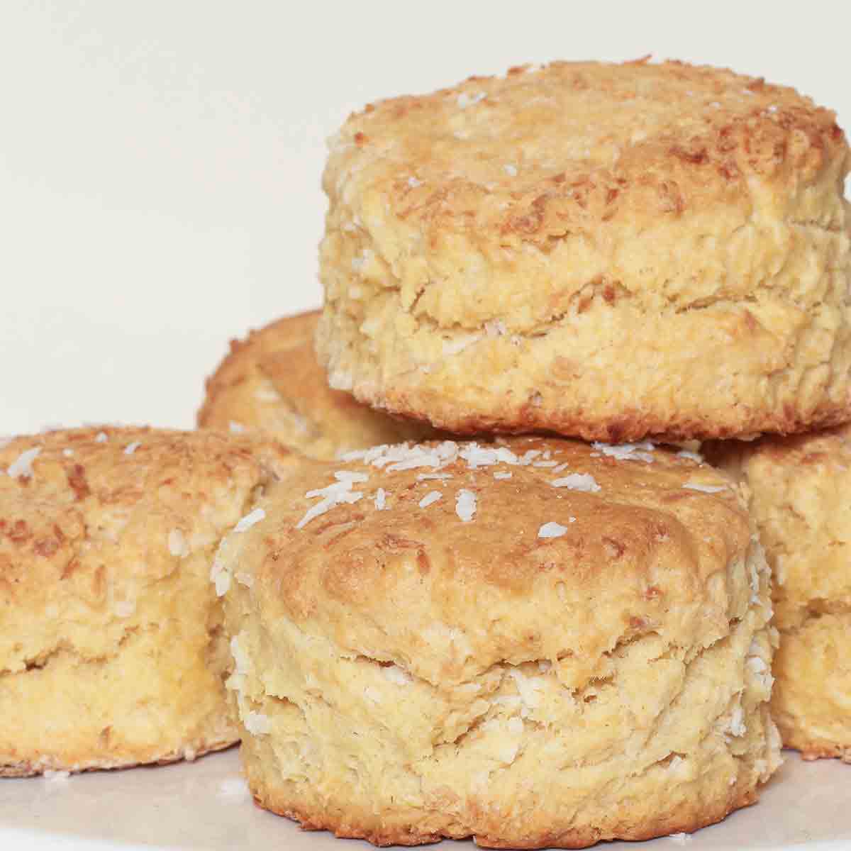A Pile Of Vegan Coconut Scones On A White Cake Stand