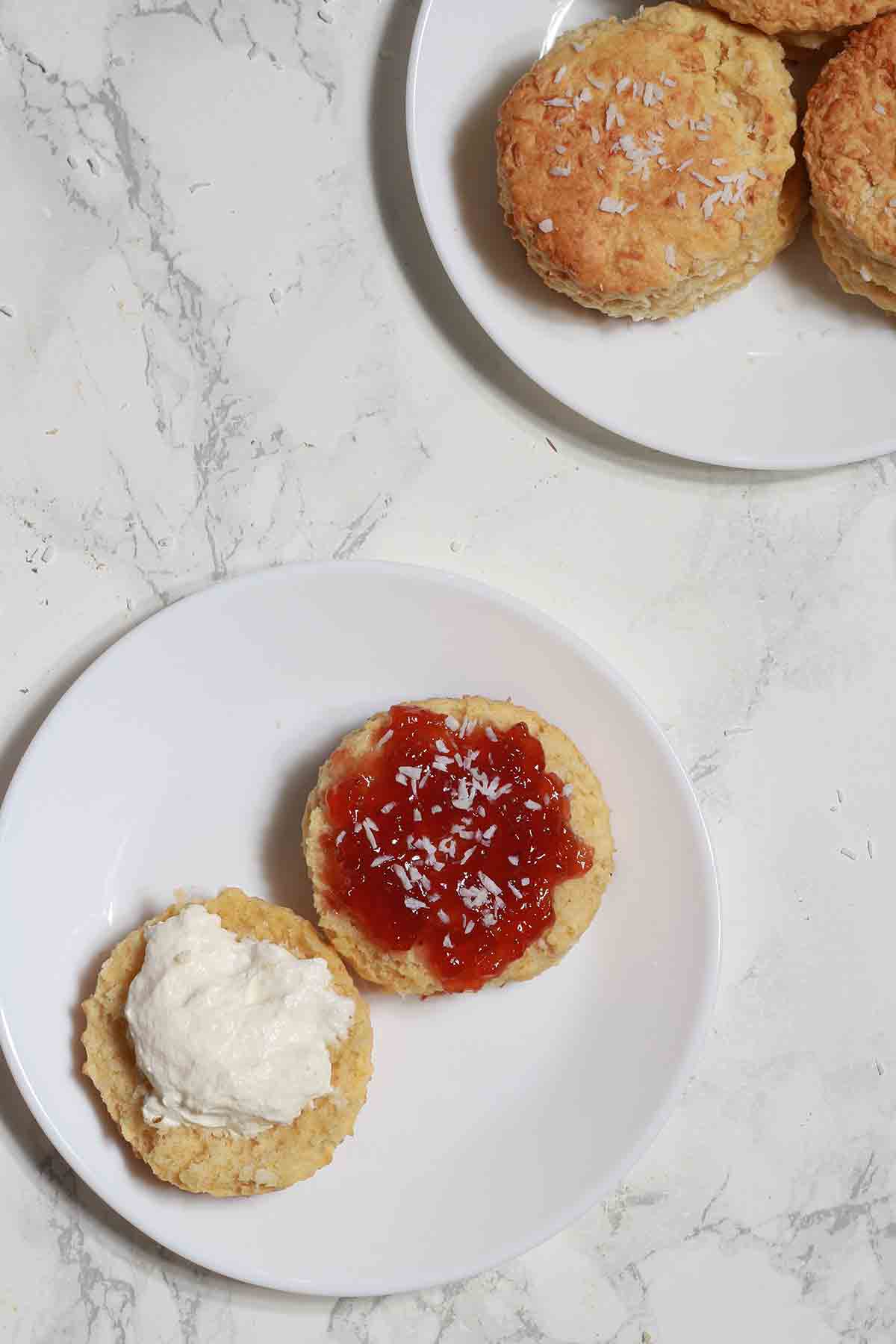 Coconut Scone On A Plate With Jam And Dairy Free Cream On Top