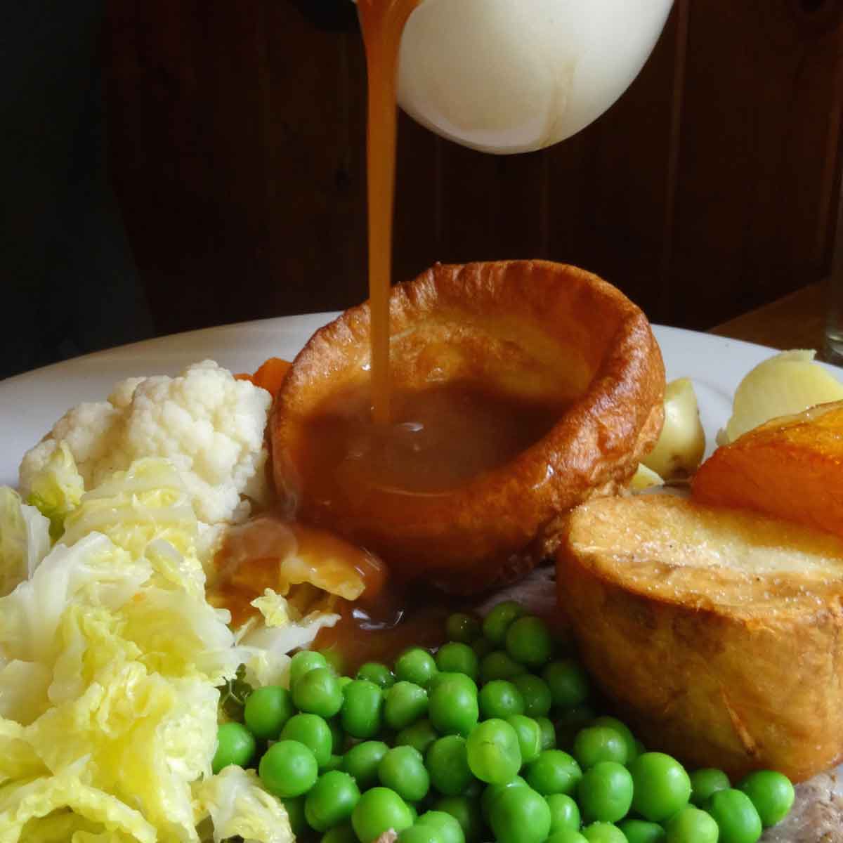 Is Vegan Gravy Feature Image Of Gravy Being Poured Into Yorkshire Gravy